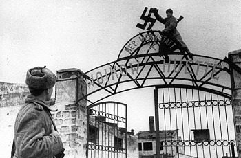 Советский солдат срывает нацистскую свастику с ворот металлургического завода им. Войкова в освобождённой Керчи